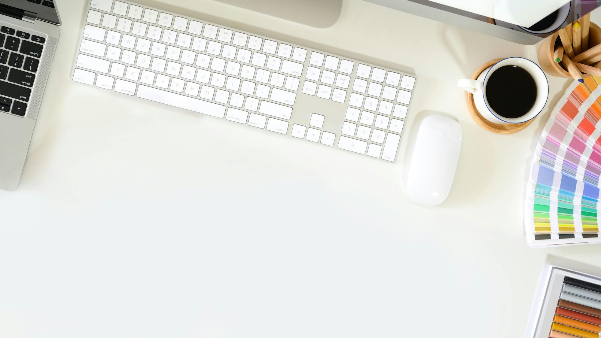 white graphic designer desk with pantone colorbook and apple computer